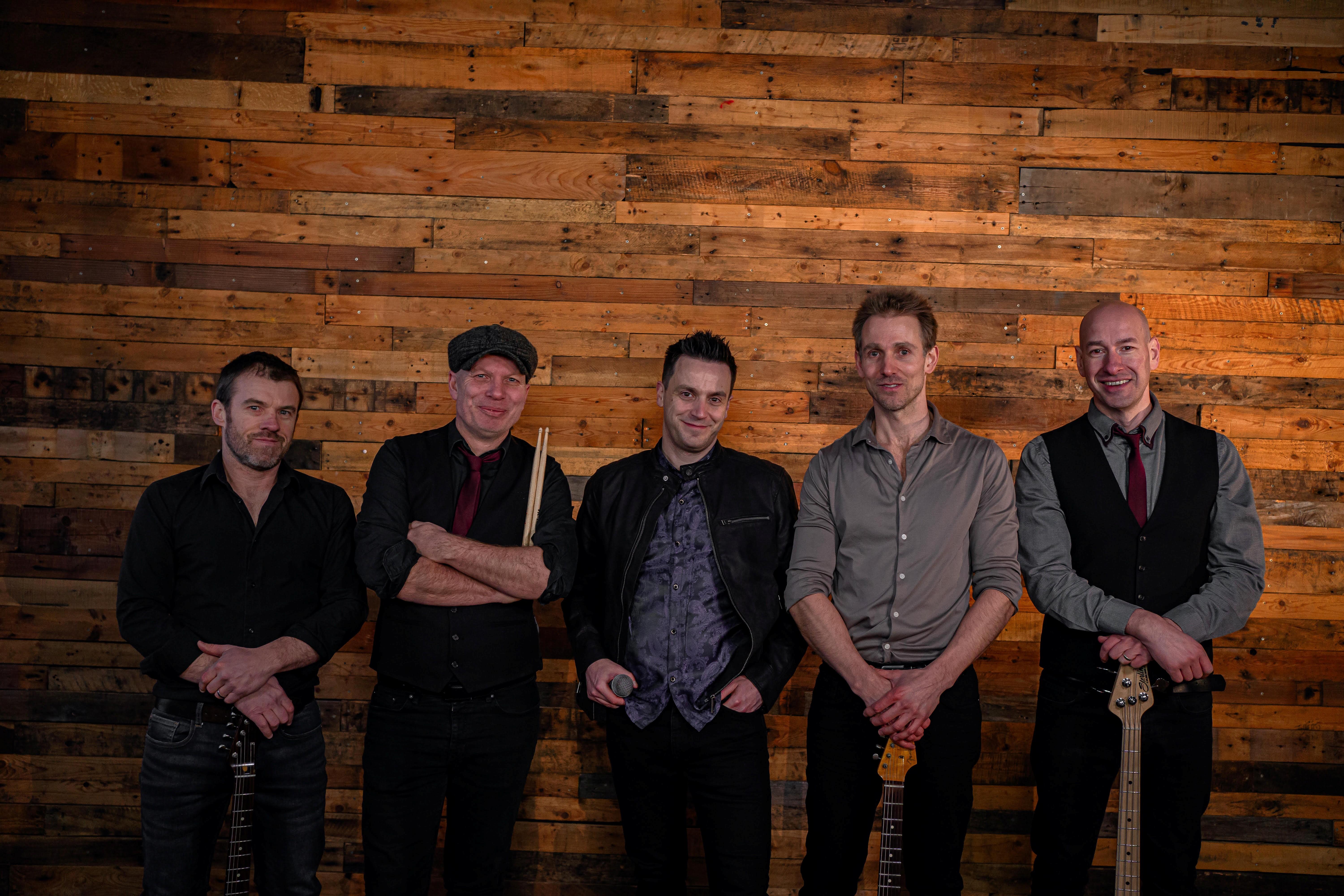 The Deadbeats band stands and smiles at the camera